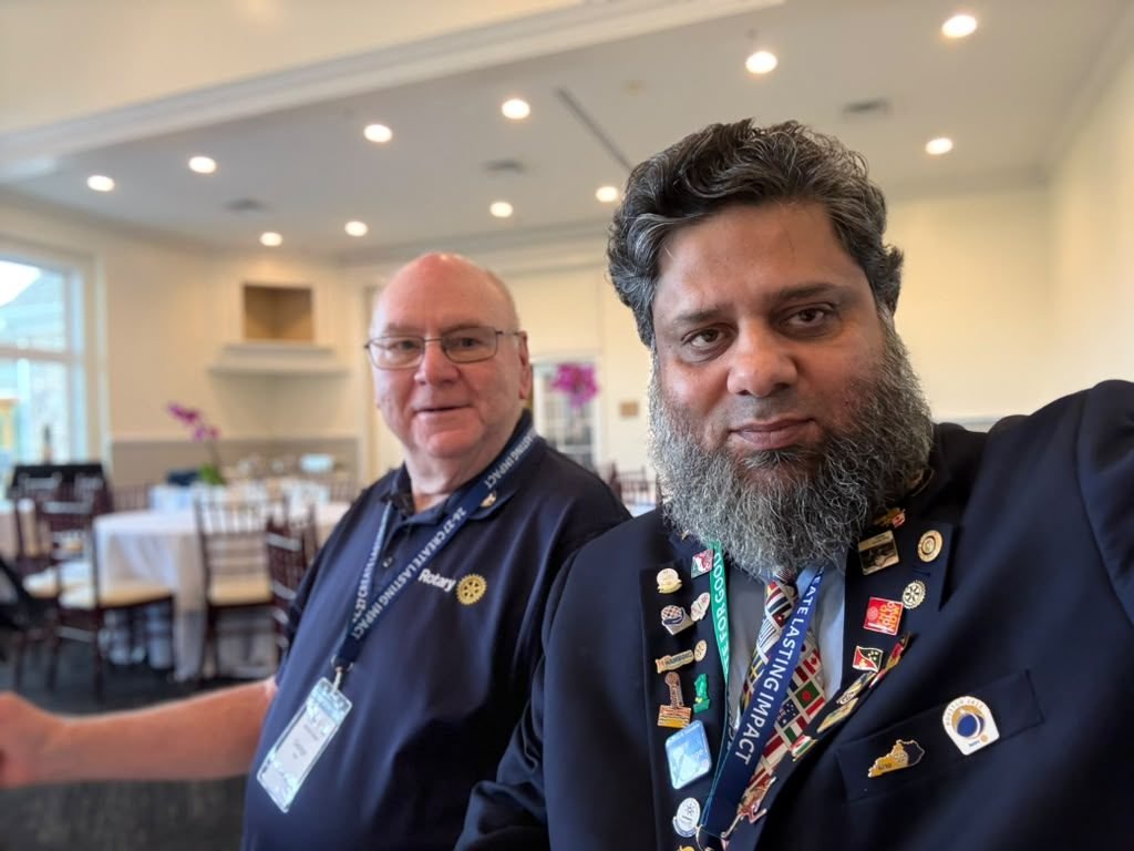 Dr. Ahmed Ejaz in a Rotary blazer with pins beside a fellow Rotarian at an event