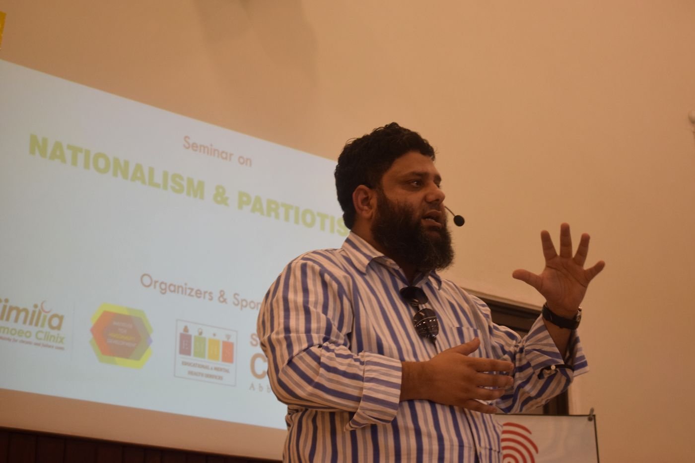 Dr. Ahmed Ejaz speaking with a headset microphone at a seminar on Nationalism and Patriotism