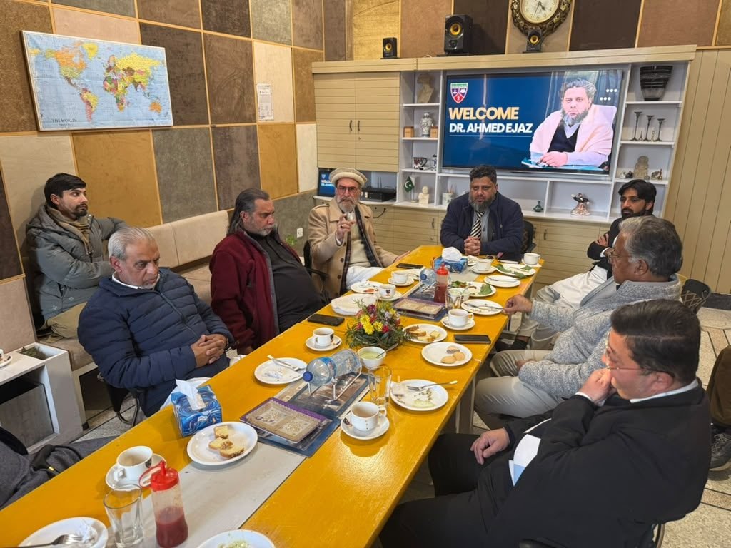 Community leaders seated around a table under a Welcome Dr. Ahmed Ejaz screen